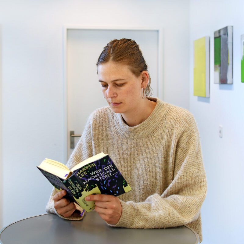 Michèle Flury steht an einem Tisch und liest in einem Buch