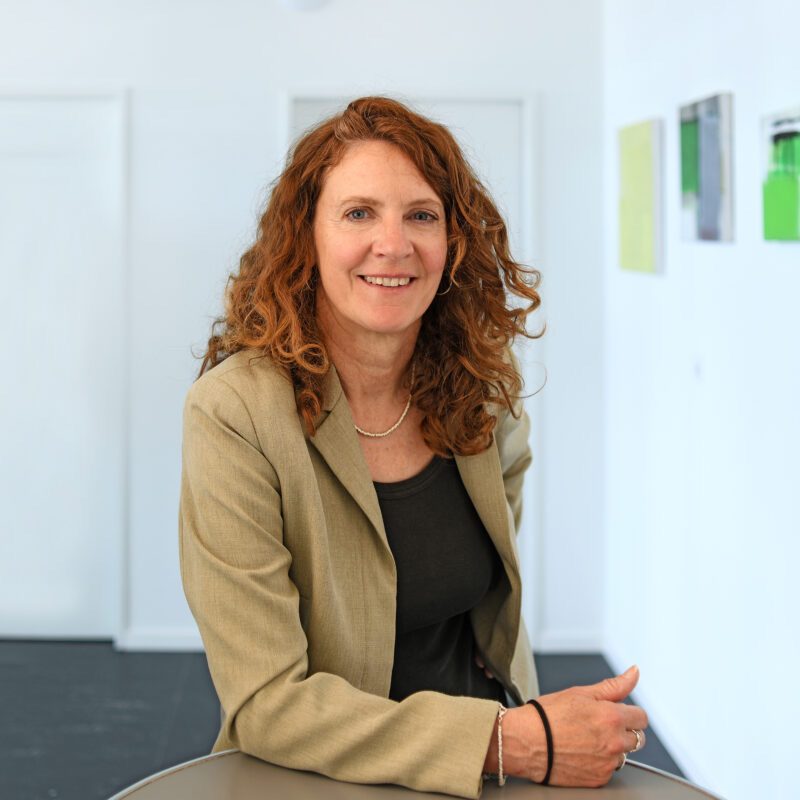 Doris Jost steht an einem Tisch und lächelt in die Kamera.