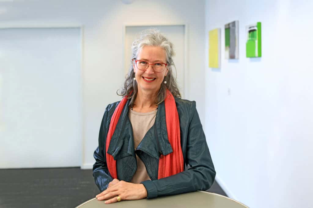 Catherine Meyer stands at a table and smiles at the camera.