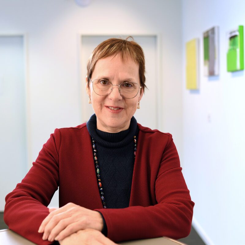Beatrice Schneider steht an einem Tisch und schaut in die Kamera.