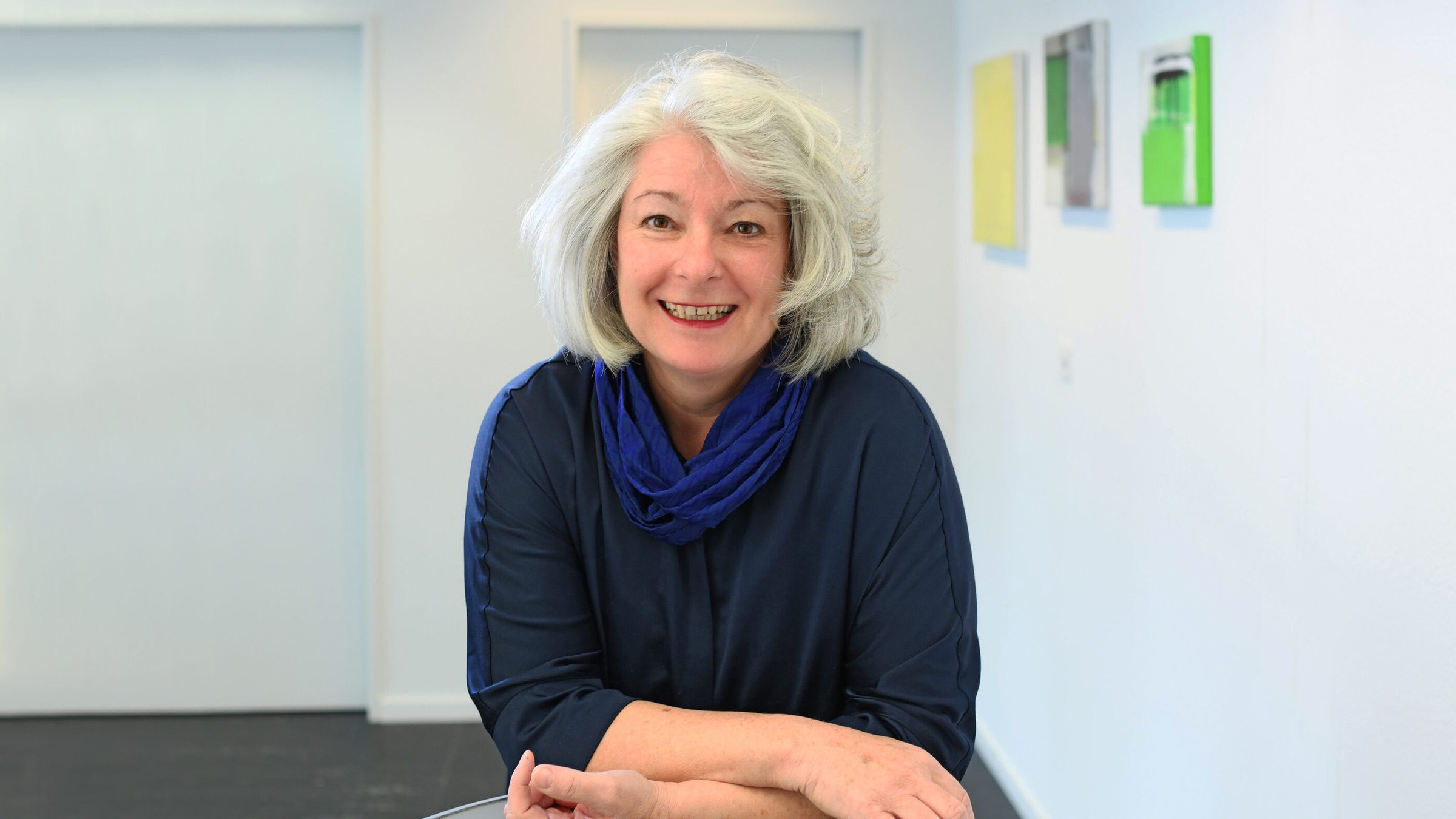 Marie-Thérèse Véron steht an einem Tisch und lächelt in die Kamera.