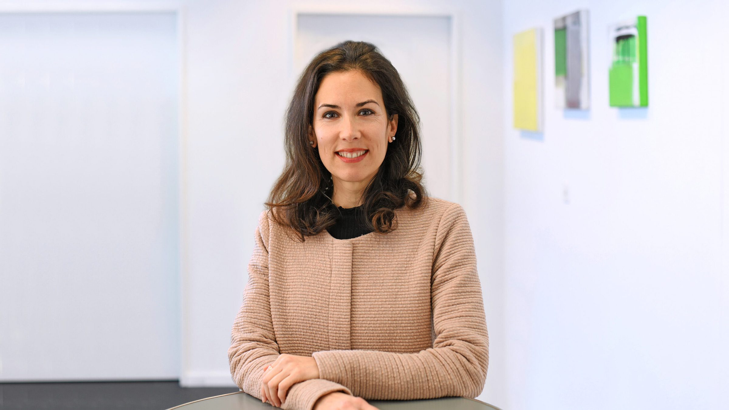 Bernadette Vidal steht an einem Tisch und lächelt in die Kamera.